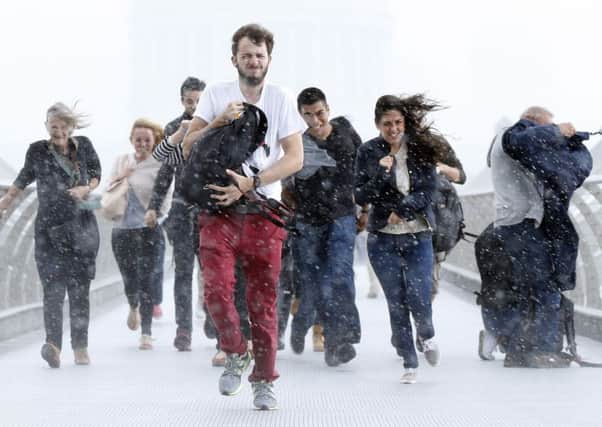 Pedestrians get caught up in high winds and torrential rain on the Millennium Bridge in Southwark, London yesterday as the remnants of Hurricane Bertha swept the south of England. Picture: PA