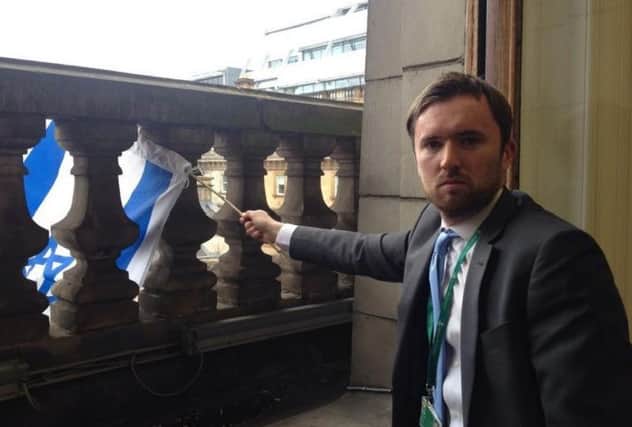 This photo from David Meikle's Twitter account shows him waving the Israeli flag from his council office balustrade. Picture: twitter.com/cllrdmeikle
