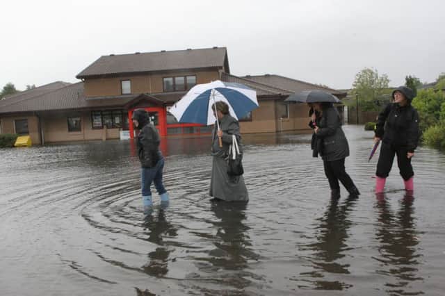 Women in Elgin try to get to work yesterday via a flooded car park. The forecast is for more unsettled weather but worst is over. Picture: TSPL
