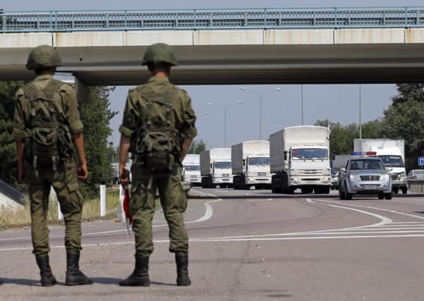Russian convoy of trucks carrying humanitarian aid for Ukraine drives along a road as Russian servicemen look on. Picture: Reuters
