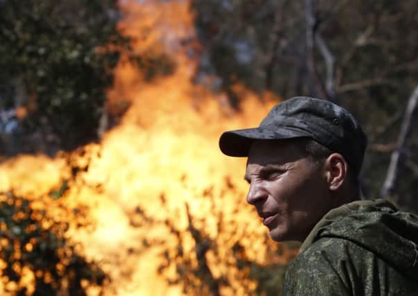 An armed pro-Russian separatist looks as flames erupt from a gas pipeline after a shelling in Donetsk. Picture: Reuters