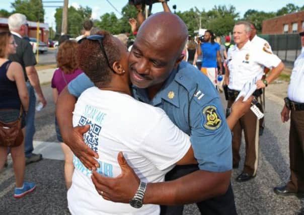 Highway Patrol Captain Ronald Johnson hugs a woman in Ferguson as tensions eased yesterday. Picture: AP