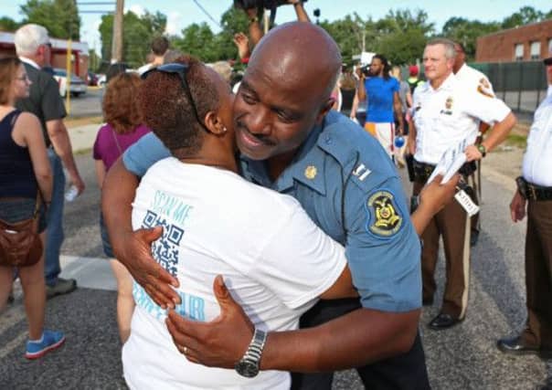 Highway Patrol Captain Ronald Johnson hugs a woman in Ferguson as tensions eased yesterday. Picture: AP