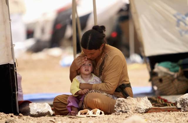 A refugee Yazidi woman, who fled the violence, sits with a child at Nowruz refugee camp in Qamishli. Picture: Reuters