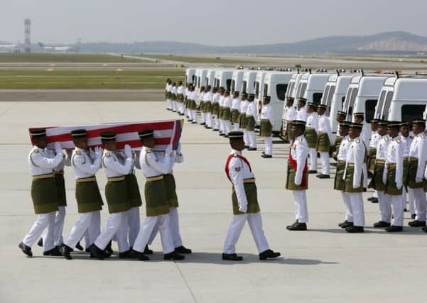 Soldiers carry one of the coffins as hearses wait. Right: Malaysia Airlines aircrew grieve. Picture:AP
