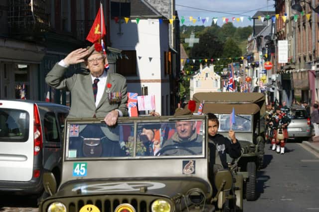 Dr Tom Renouf salutes crowds during parades in Normandy after being awarded the Legion dHonneur