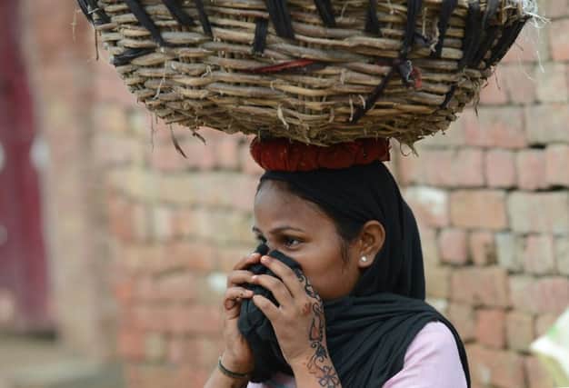 One of Indias lowcaste scavengers covers her face as she carries away a basket of human excrement on her head. Picture: Getty