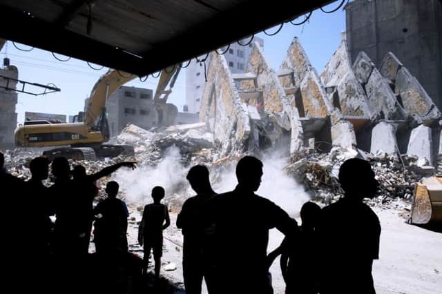 Palestinians watch as rubble from a building that was targeted by Israeli air strikes is cleared in Gaza City. Picture: Getty