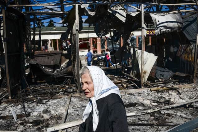 A woman passes by shops burned by shelling near the train station in Donetsk, Ukraine, Saturday, Aug. 30, 2014. Heavy shelling from an unknown source hit a railway station and a nearby market on Friday evening in Donetsk, the largest rebel-held city in eastern Ukraine, an OSCE observer said at the site. (AP Photo/Mstyslav Chernov)