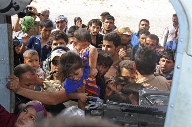 Iraqi Turkmens try to board an Iraqi Army helicopter aid flight bringing in supplies to Amirli. Picture: AP
