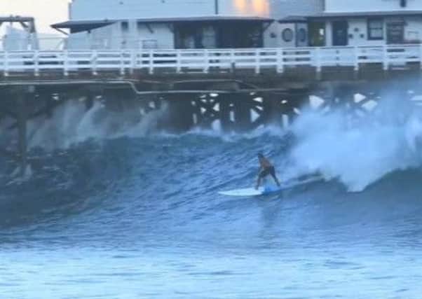 Surfer Laird Hamilton rides a wave through Malibu Pier, August 2014.