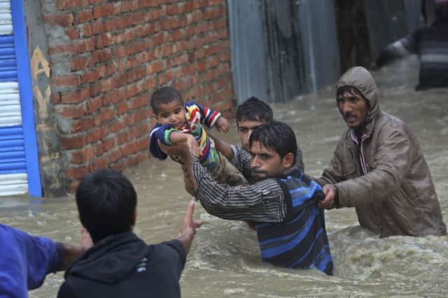 Men carry a boy to safety and use boats to negotiate the flood waters in Srinagar. Picture: AP