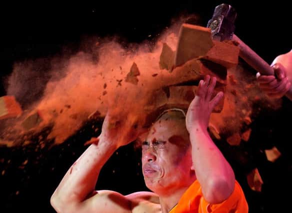 Shaolin warrior smashes bricks over his head to show strength from training. Picture: David Moir