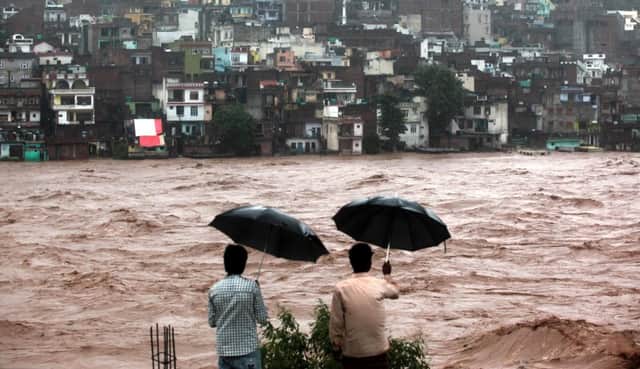 Two men watch a rainswollen river in Jammu from a safe vantage point. Picture: AFP/Getty