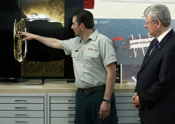 Stephen Harper (R) listens as Parks Canada's Ryan Harris talks about an image showing one of the expedition's ships. Picture: Reuters