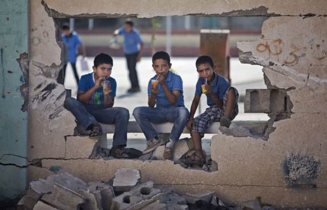 Three pupils enjoy a drinks break  war damage to schools in Gaza has been extensive. Picture: AP