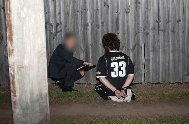 A police officer, one of 800 involved in yesterdays raids, interrogates one of the suspects. Picture: Reuters