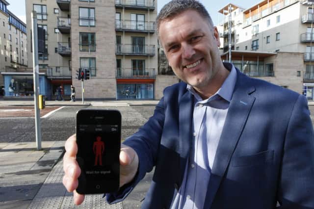 Gavin Neate holds a smartphone showing the app he designed. Picture: Toby Williams