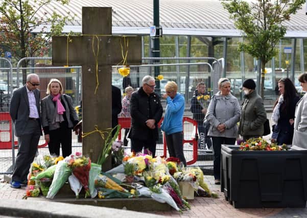 Members of the public observe the floral tributes at the base of the Eccles Cross for murdered aid worker Alan Henning in Eccles. Picture: Getty