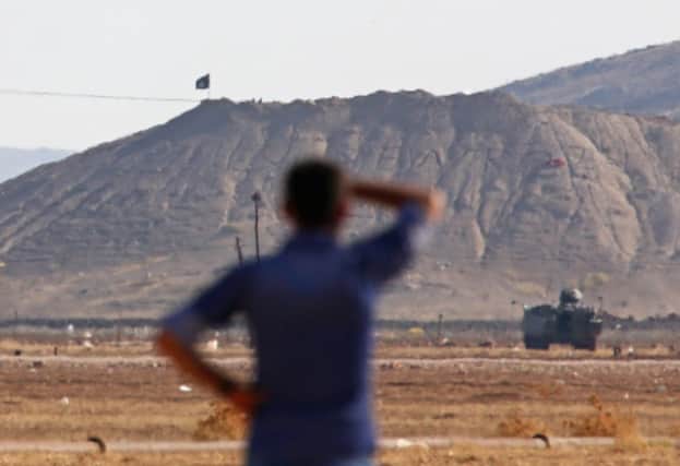 The sinister flag is visible from across the Turkish border, where tanks are lined up. Picture: Getty