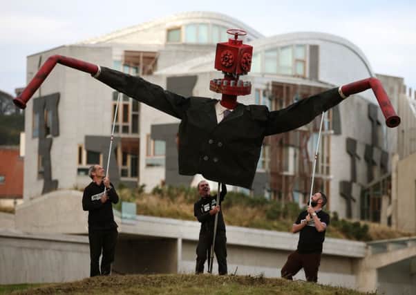 A 10ft 'pro-fracking puppet monster' called Mr Frackhead is held above the Scottish Parliament at Holyrood. Picture: PA