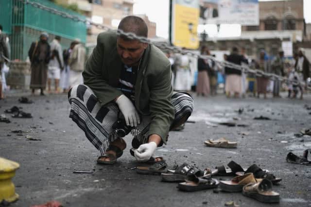Sandals lie scattered as a Yemeni security official inspects the scene of the explosion in Sanaa. Picture: AP