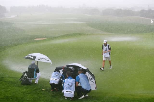 Players and caddies shelter on the flooded second green during the final round. Picture: Francisco Leong/Getty