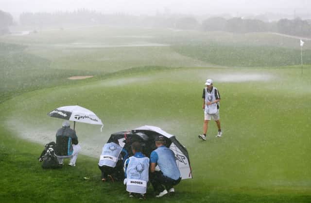 Players and caddies shelter on the flooded second green during the final round. Picture: Francisco Leong/Getty