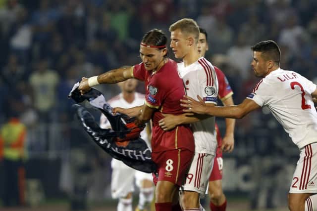 Serbia's Nemanja Gudelj, left, holds a flag as he and Albania's Bekim Balaj, centre, clash. Picture: AP
