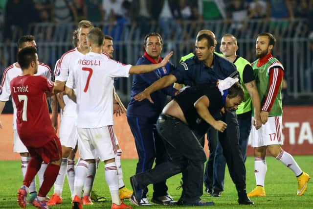 A policeman escorts a Serbian fan that invaded the pitch. Picture: AFP
