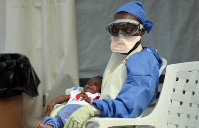 A Liberian health worker holds a baby infected with the Ebola virus as the UK calls for more aid. Picture: AFP