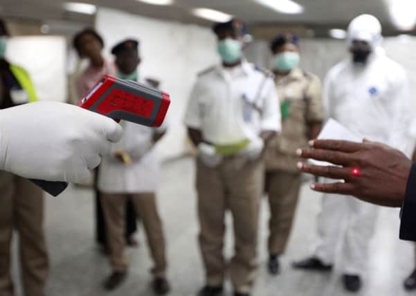 A Nigerian health official uses a thermometer on a worker at the arrivals hall of Murtala Muhammed International Airport in Lagos, Nigeria. Picture: AP