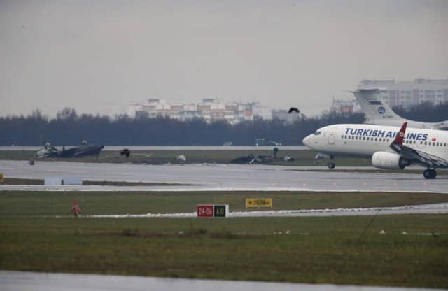 A plane takes off at Vnukovo airport in front of the wreckage of the private jet. Picture: Reuters