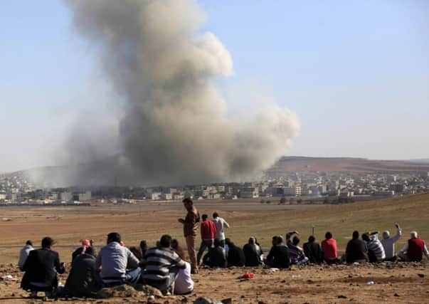 People watch as smoke and dust rise over Syrian town of Kobani on the Turkish-Syrian border. Picture: Getty