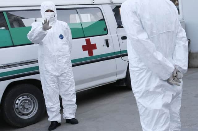 Medical personnel in protective suits standing by an ambulance. Picture: AP