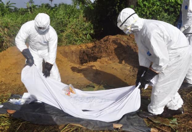 Health workers prepare to place body of a man suspected of dying from the Ebola. Picture: AP