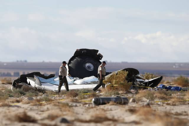 Sheriffs deputies pass debris as they walk the crash site. Picture: Reuters