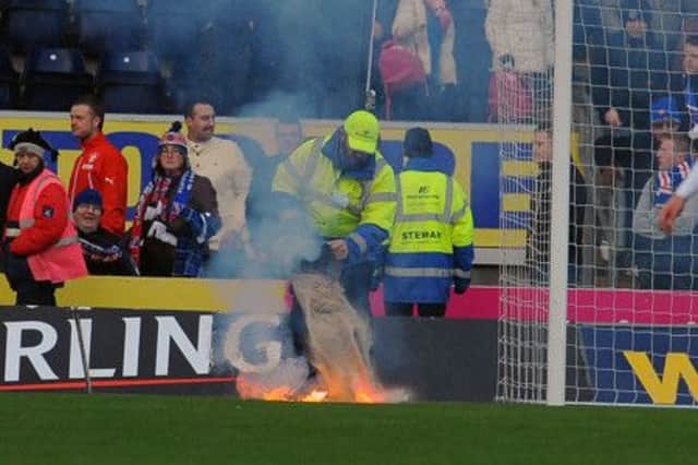 A steward deals with flares thrown onto the pitch at the match. Picture: Gary Hutchison