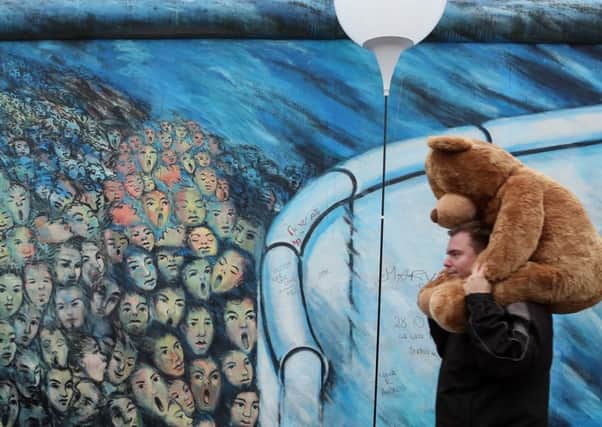 A visitor walks by East Side Gallery, a section of the former Berlin Wall, during celebrations. Picture: Getty