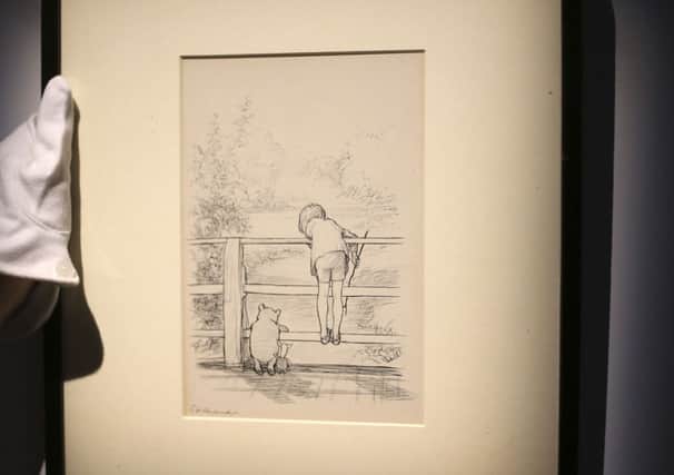 A Sotheby's gallery technician hangs a drawing at the auction house in central London by EH Shepard of Winnie the Pooh. Picture: AP