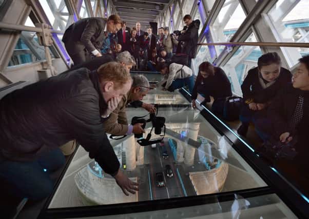 Members of the media capture the view from the newly installed glass floor 138 feet above the River Thames at Tower Bridge. Picture: PA
