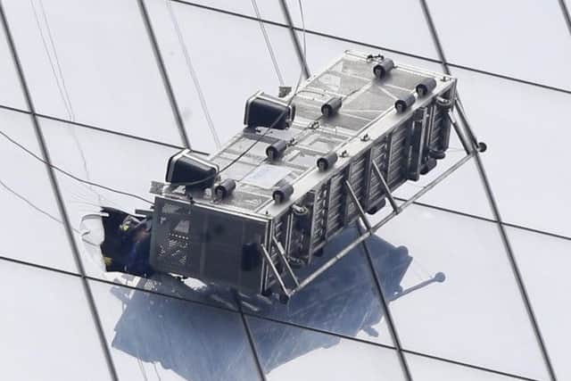 A firefighter reaches through a cut-out window into a dangling work basket. Picture: AP
