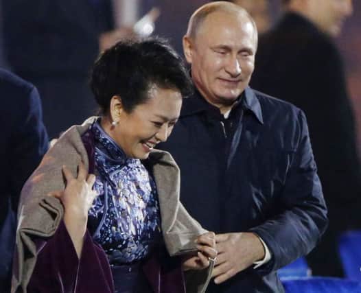 President Vladimir Putin, right, puts a shawl on Peng Liyuan. Picture: AP