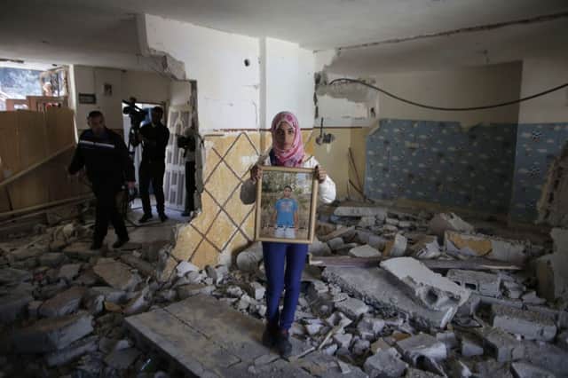 Relative of Abdel Rahman al-Shaludi holds his portrait amid rubble of the family home. Picture: Getty