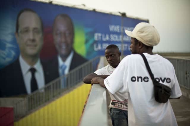 Two men stand in front of billboard featuring François Hollande and his Guinean counterpart Alpha Condé. Picture: AP