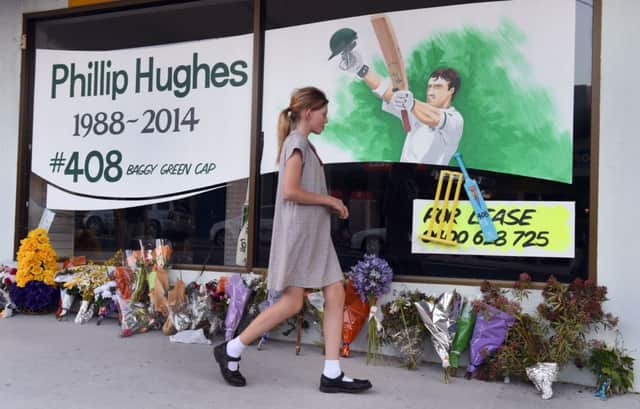 A schoolgirl walks past a tribute to Phillip Hughes, who was due to be buried overnight UK time, days after his tragic death. Picture: Getty