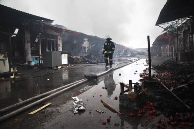 A firefighter walks through the burnt-out market and its piles of ruined goods in central Grozny after the fire. Picture: AP
