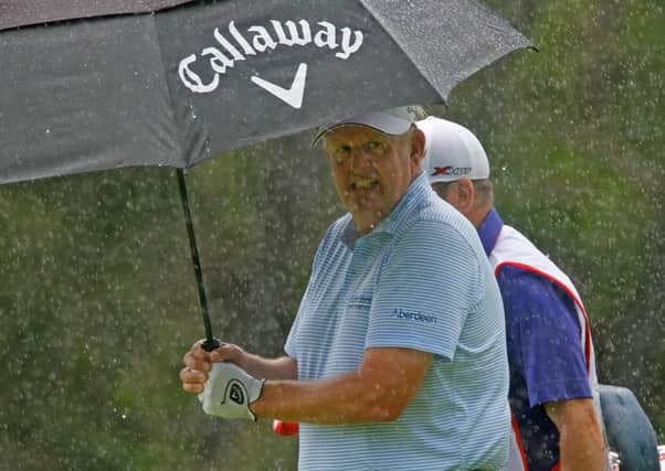 Colin Montgomerie shelters under his umbrella during a shower in the opening round in Mauritius. Picture: Getty