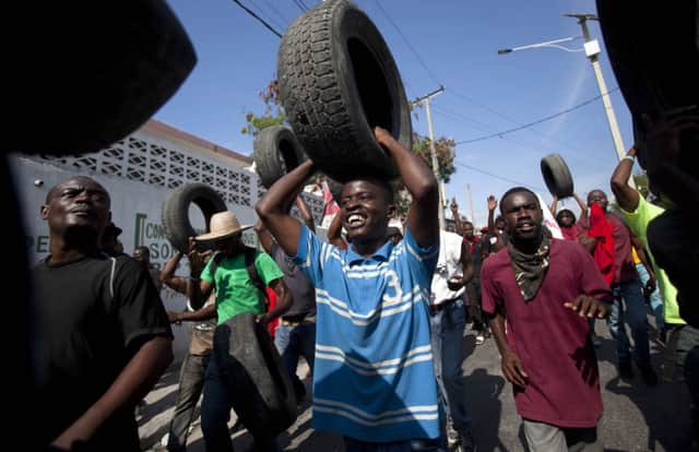 Anti-government protesters carry tyres to set fire to at road blocks in Haitis capital Port-au-Prince at the weekend. Picture: AP