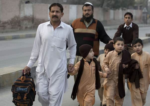 Pakistani parents escort their children outside a school attacked by the Taliban in Peshawar, Pakistan. Picture: AP